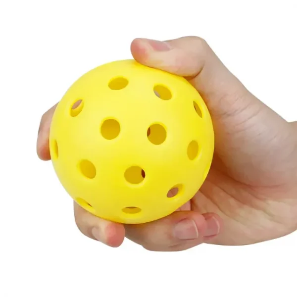One of many yellow outdoor pickleball balls in a person’s hand