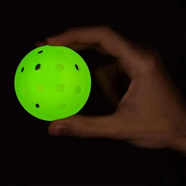 Green luminous pickleball ball in a person’s hand.