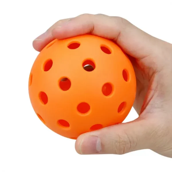 One of many orange outdoor pickleball balls in a person’s hand
